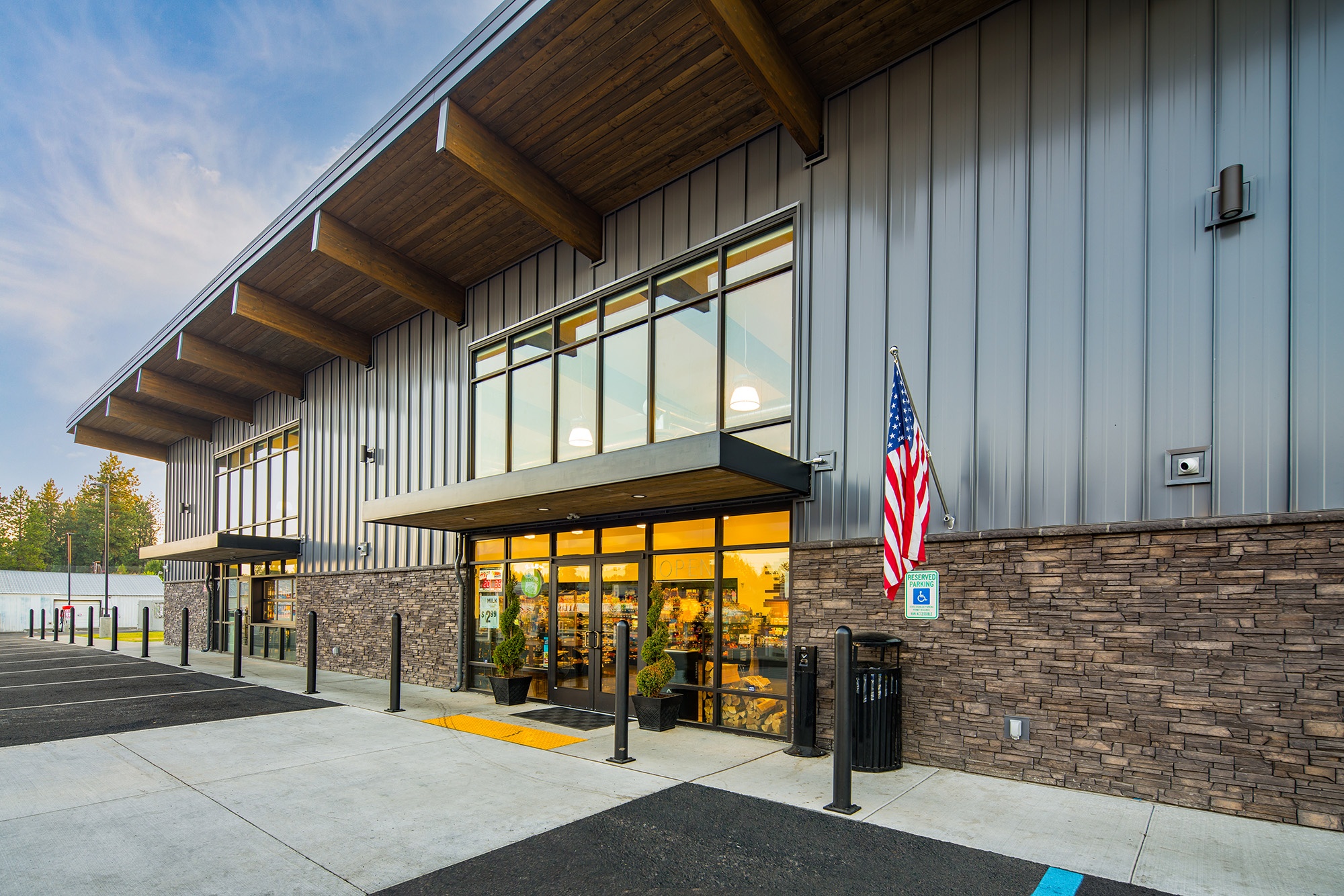 Angled entry view of Atlas Seltice Gas Station in Coeur d’Alene with glass storefront doors, stone cladding, and extended roof canopy
